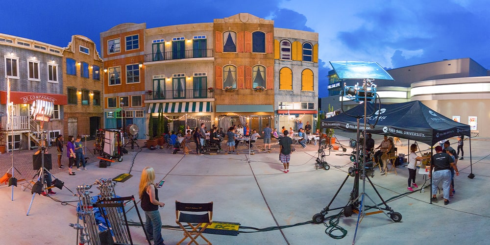 A film set on the backlot at Full Sail University with film crew, lights, cameras, director chair, and tent.